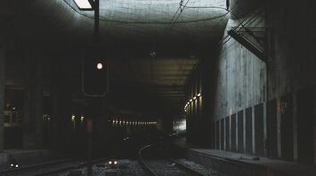Interior of a dark railway tunnel with a red signal light