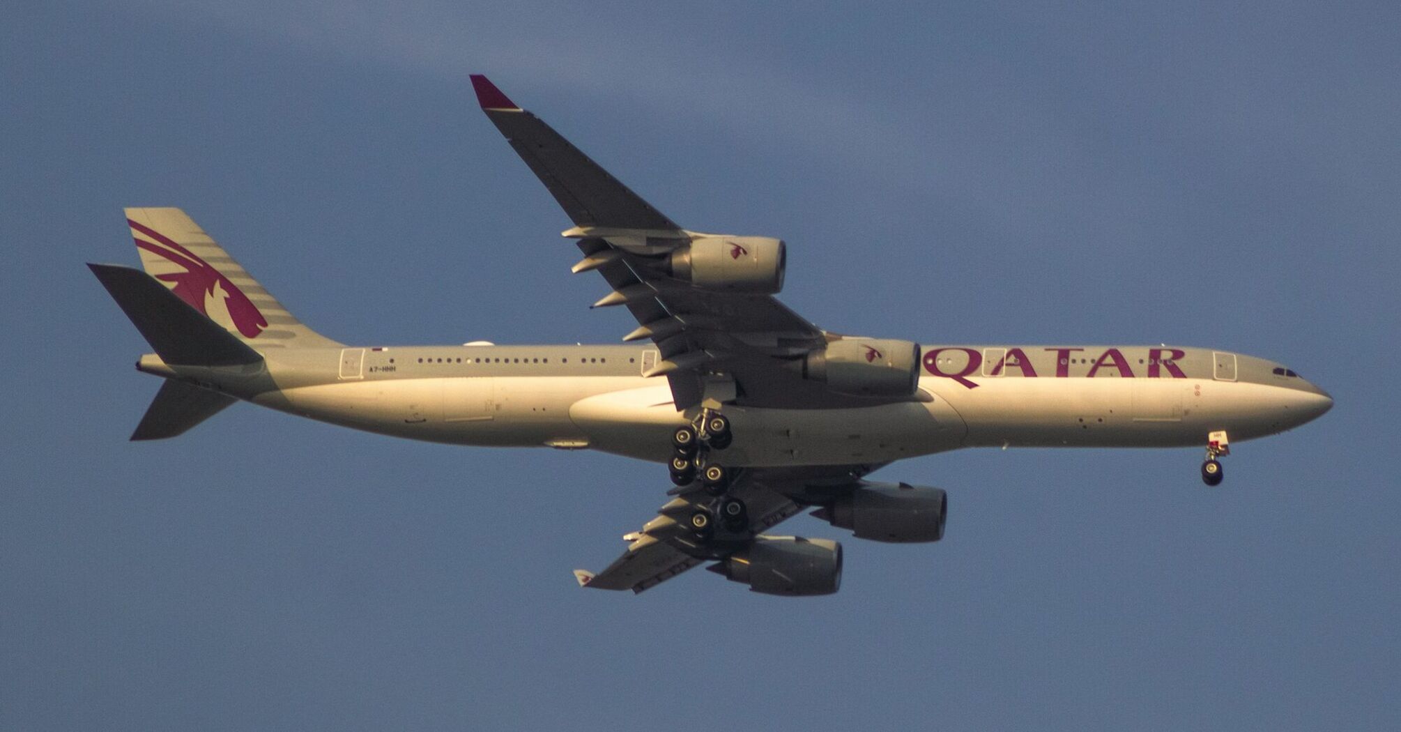 Qatar Airways airplane mid-flight with landing gear extended