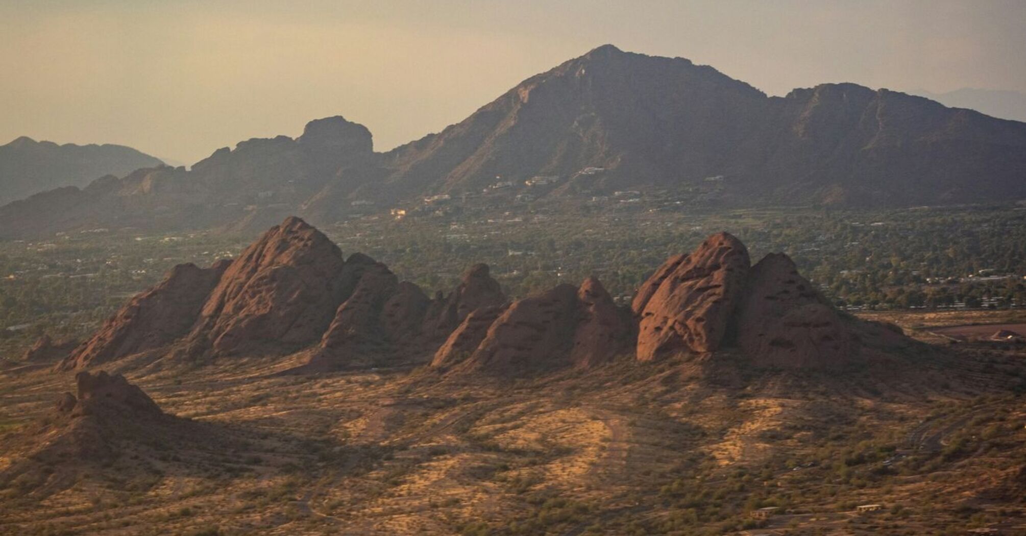 A scenic view of a desert landscape with rocky formations in the foreground and mountains in the background under a cloudy sky in Scottsdale