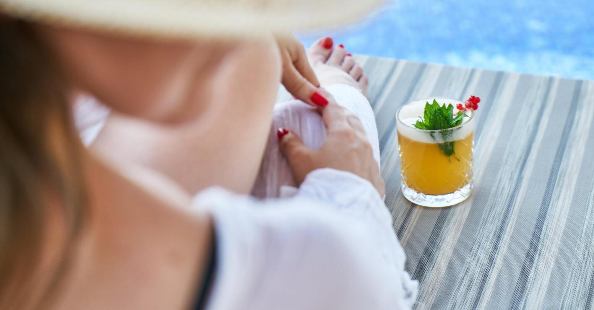 Woman relaxing by a pool with a tropical drink