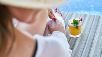 Woman relaxing by a pool with a tropical drink