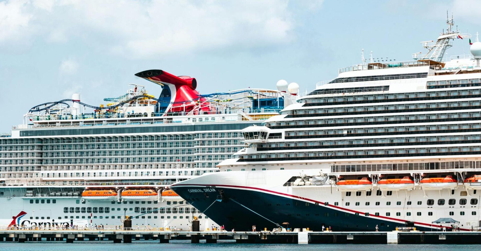 Two large cruise ships docked at a port under a partly cloudy sky