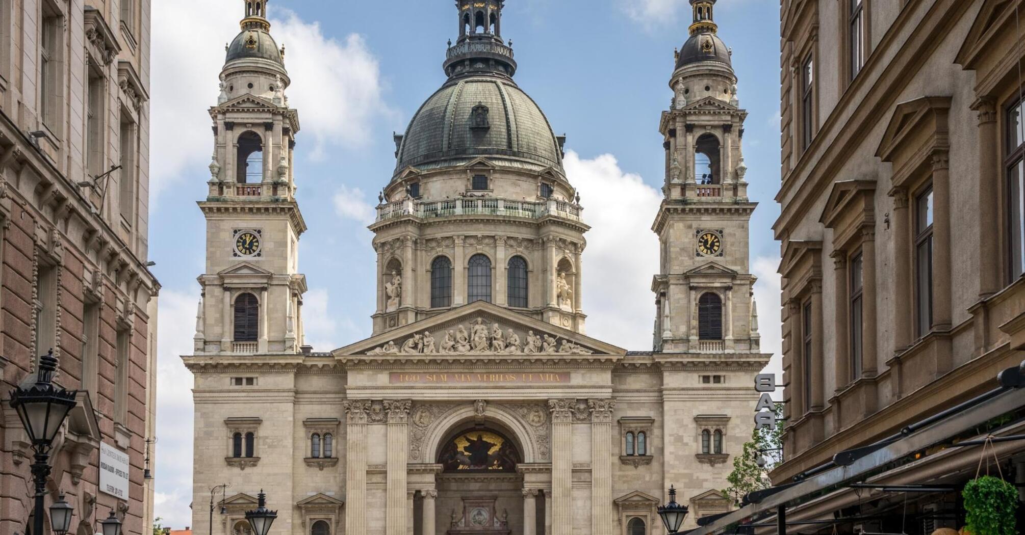 View of St. Stephen's Basilica in Budapest, Hungary, seen from a narrow street lined with cafes