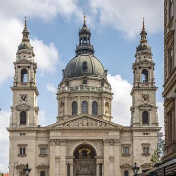 View of St. Stephen's Basilica in Budapest, Hungary, seen from a narrow street lined with cafes