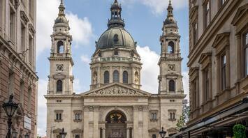 View of St. Stephen's Basilica in Budapest, Hungary, seen from a narrow street lined with cafes