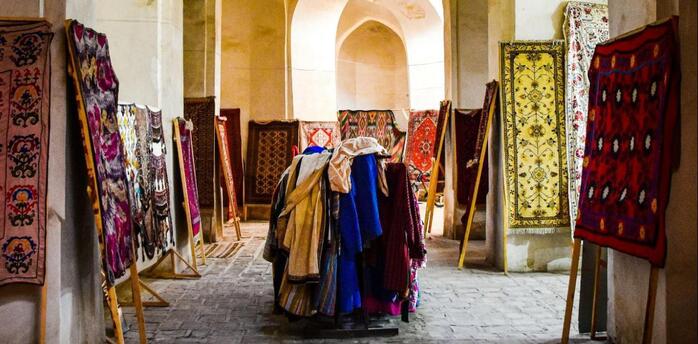 A traditional market stall displaying vibrant textiles and rugs inside an arched historical building