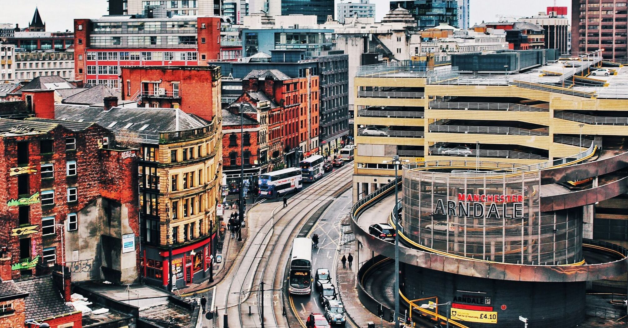 A view of central Manchester, showing trams, historic buildings, and the Arndale shopping center