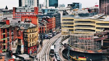 A view of central Manchester, showing trams, historic buildings, and the Arndale shopping center