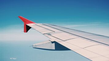 A view of an airplane wing against a clear blue sky during flight
