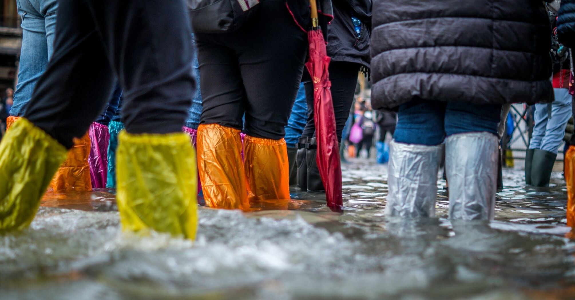 People walking through floodwater in colorful rain boots