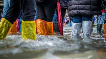 People walking through floodwater in colorful rain boots