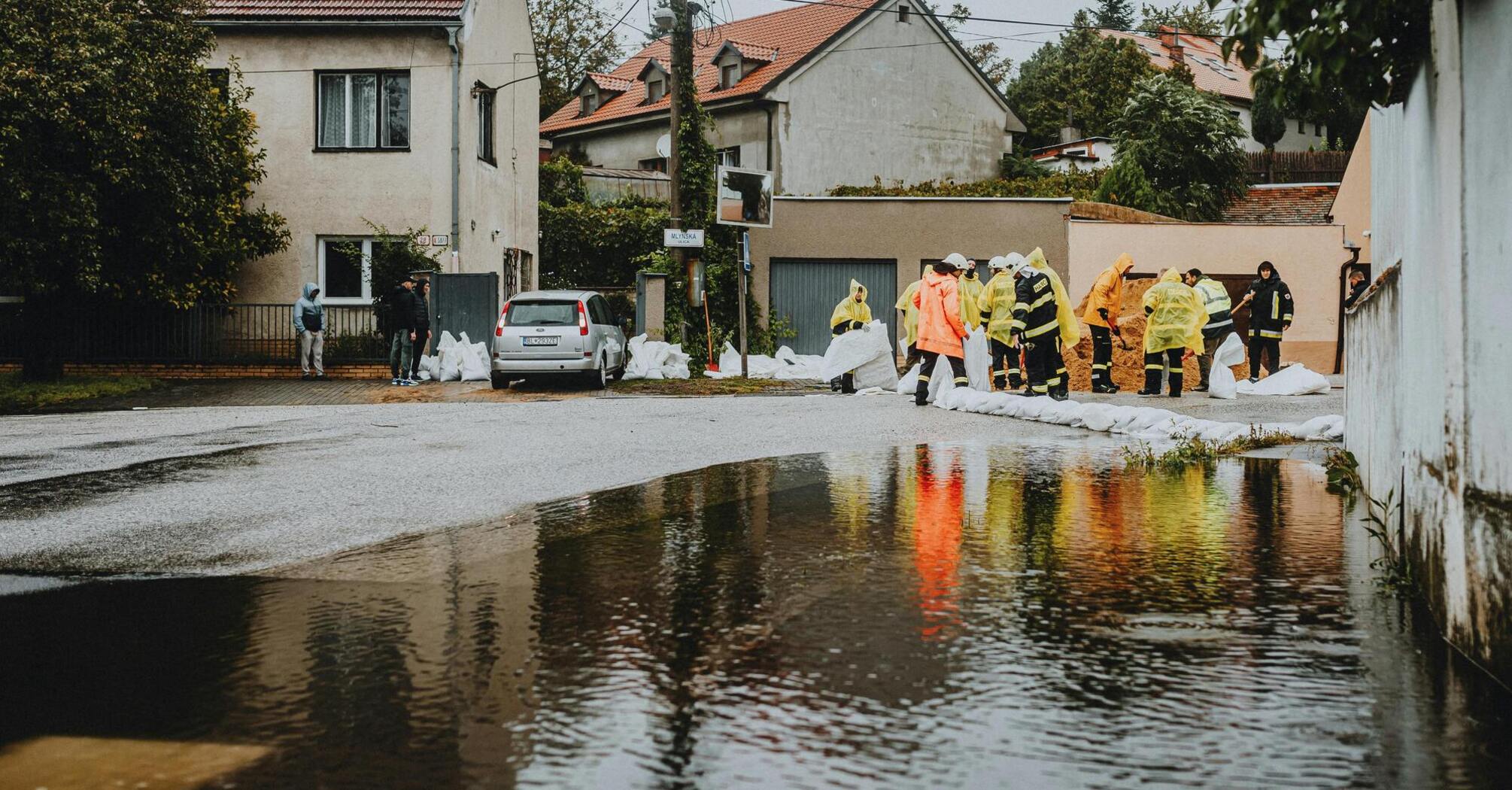 Emergency workers laying sandbags during flood response near a residential area