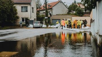 Emergency workers laying sandbags during flood response near a residential area