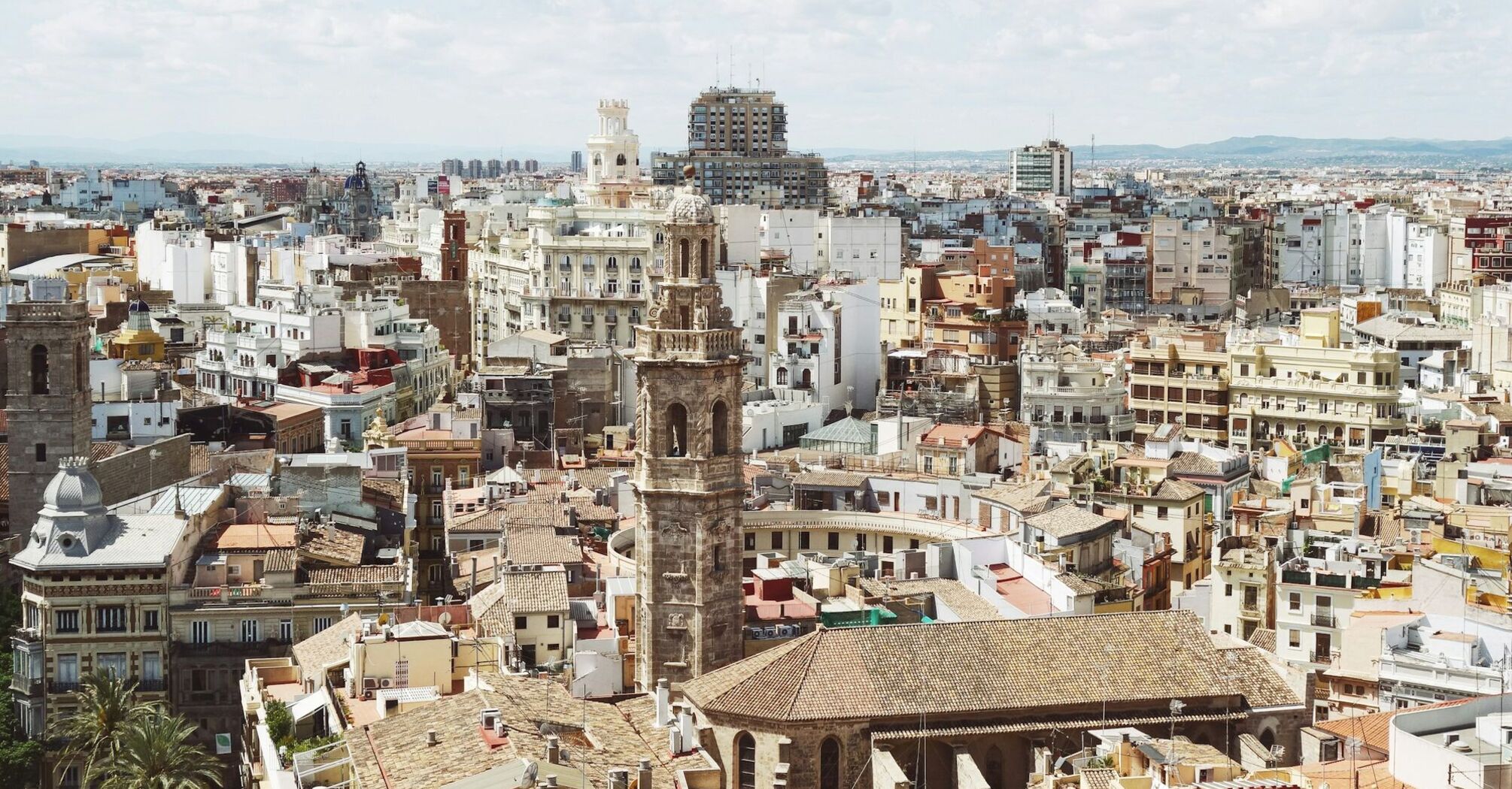 A panoramic view of Valencia, showcasing its historic buildings, bell towers, and the urban landscape under a clear sky