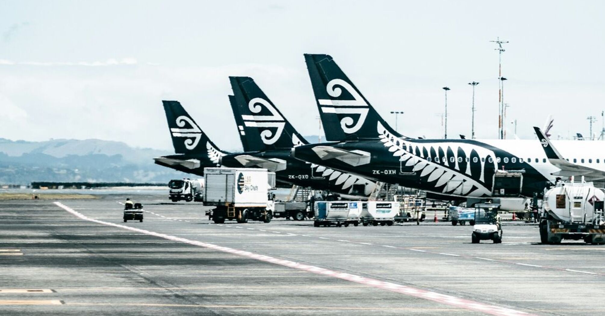 Air New Zealand planes lined up on an airport runway, preparing for international flights