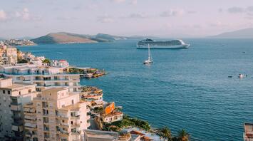 Aerial view of a coastal town with modern white buildings and a large cruise ship in the sea