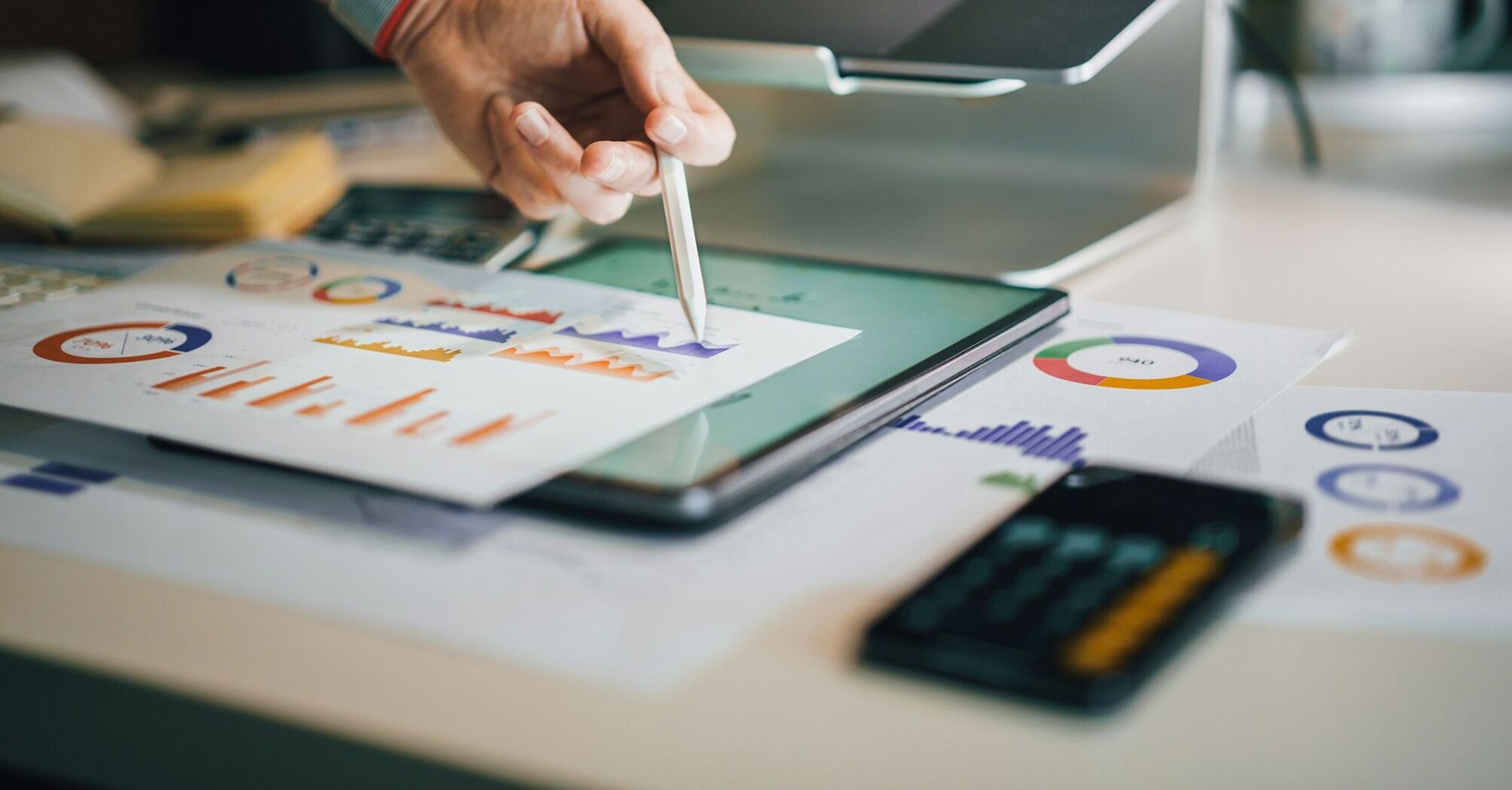 Person analyzing graphs and charts on paper and tablet