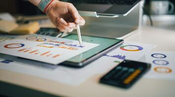 Person analyzing graphs and charts on paper and tablet