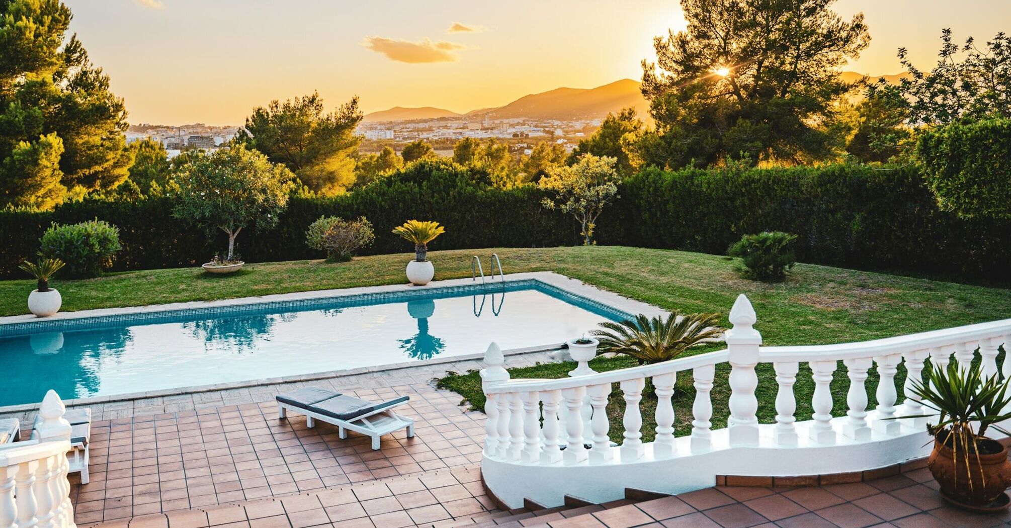 Sunset view of a pool and distant hills from a villa