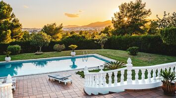 Sunset view of a pool and distant hills from a villa