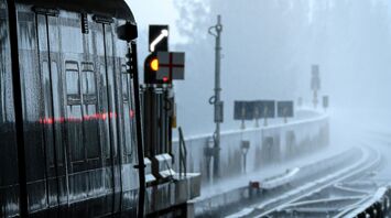 A train station in heavy rain with wet tracks and dim lighting, creating a somber atmosphere