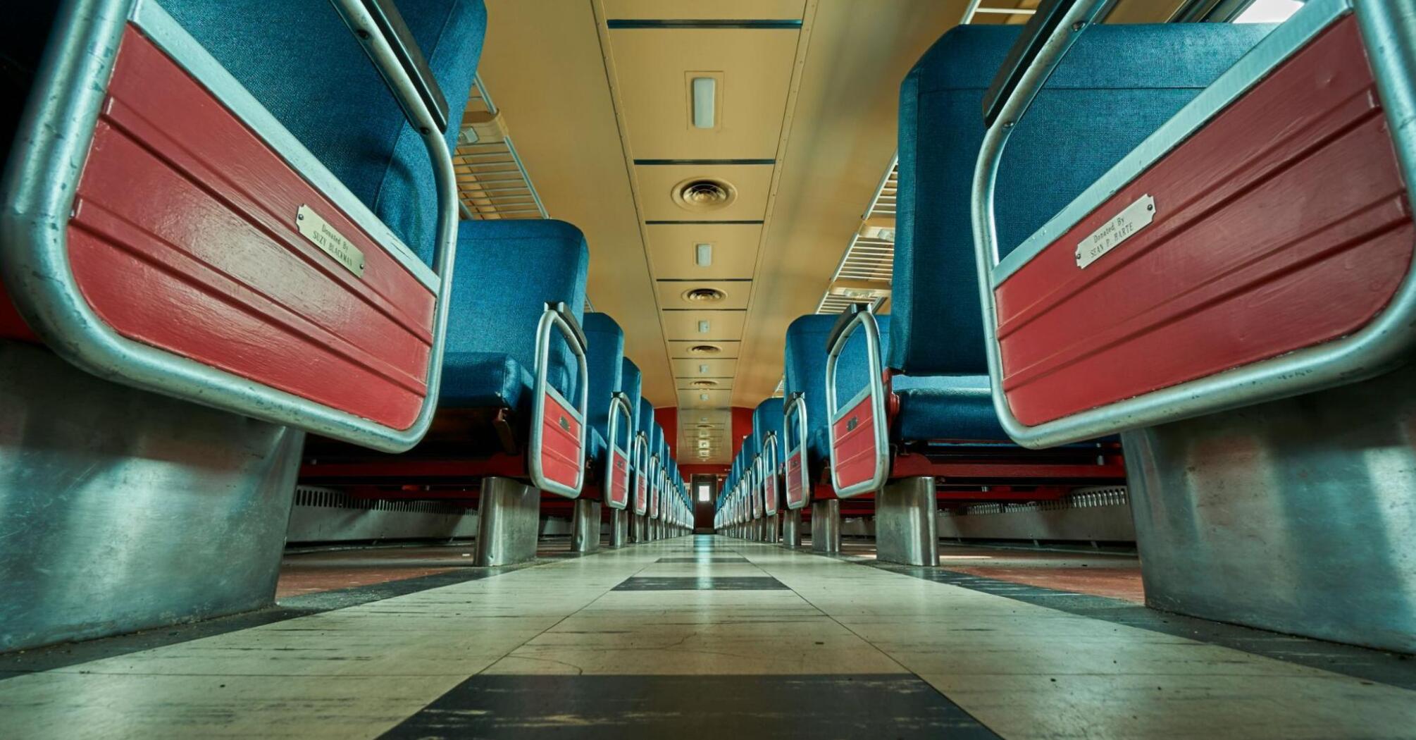 View of an empty train carriage with blue and red seats from a low angle