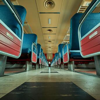 View of an empty train carriage with blue and red seats from a low angle
