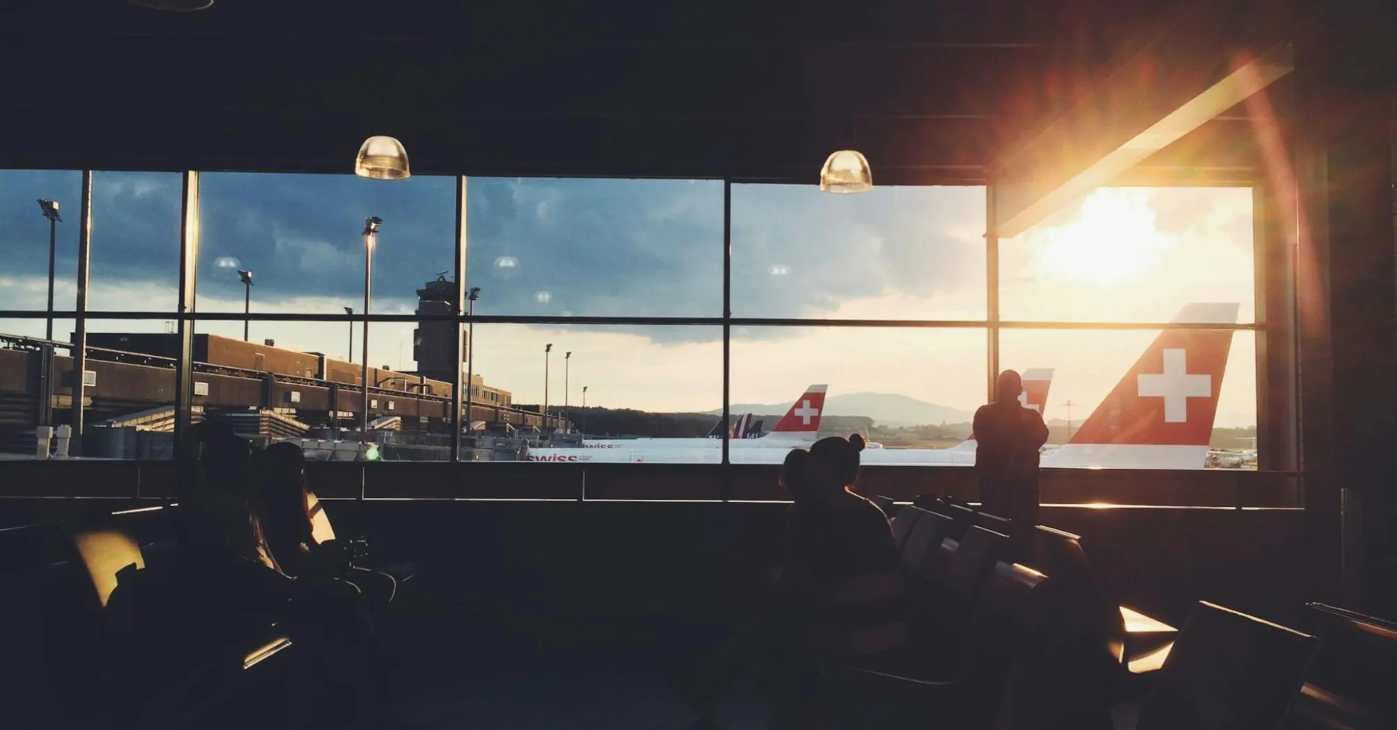 Airport passengers waiting near Swiss aircraft at sunset