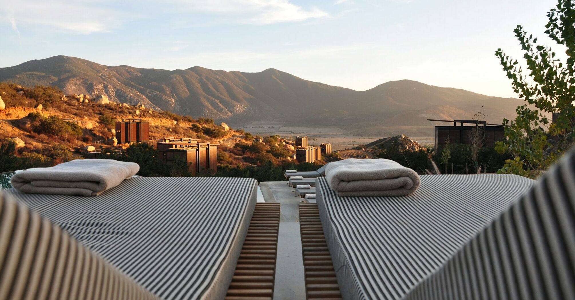 Sunset view over mountains from resort with outdoor lounge beds