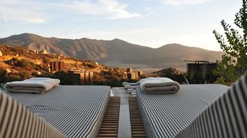 Sunset view over mountains from resort with outdoor lounge beds