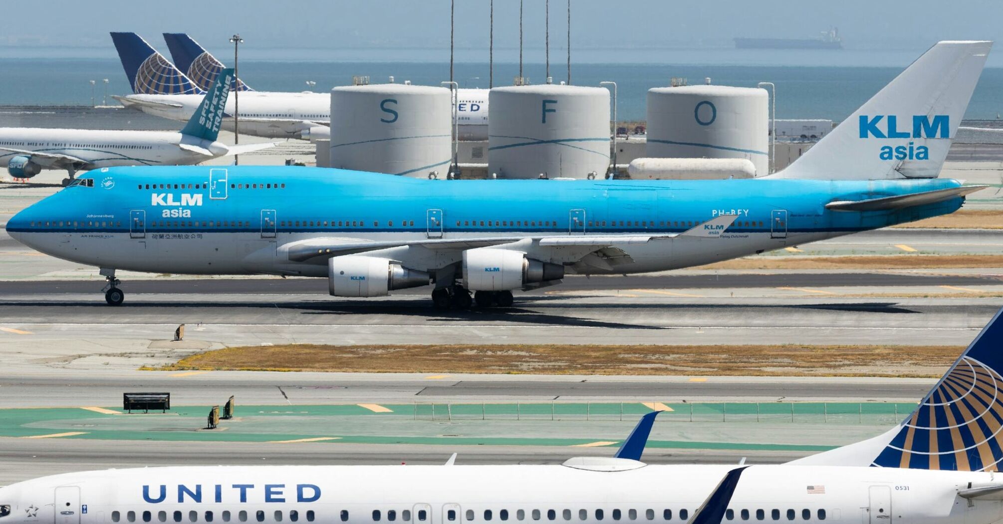 KLM plane taxiing at an airport alongside United Airlines planes