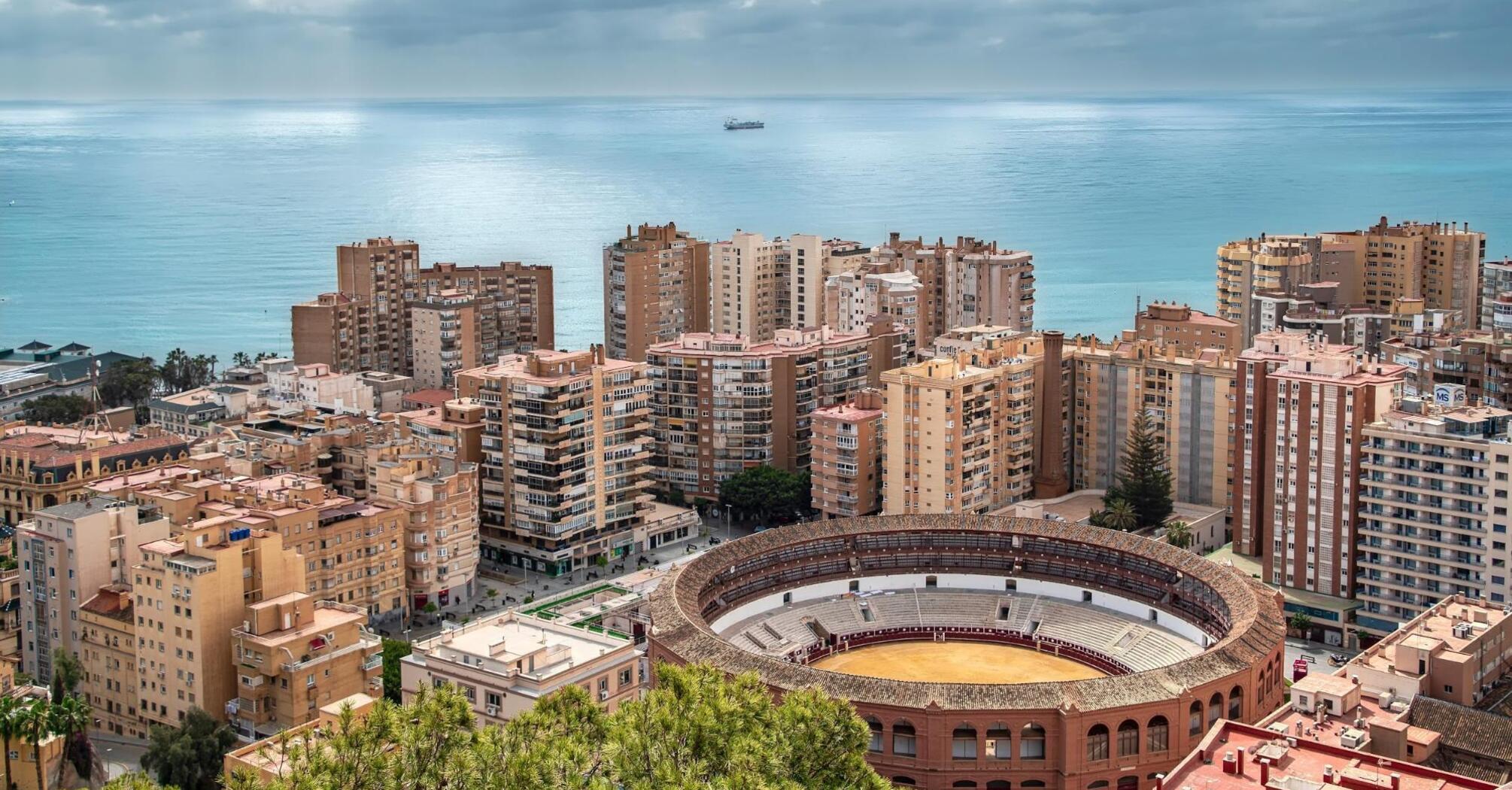 Overlooking Malaga from above, with high-rise buildings densely packed around a bullring near the sea