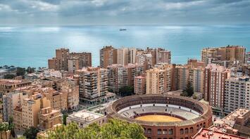 Overlooking Malaga from above, with high-rise buildings densely packed around a bullring near the sea
