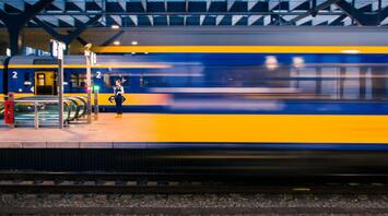 A high-speed train speeding past a modern platform at a European station