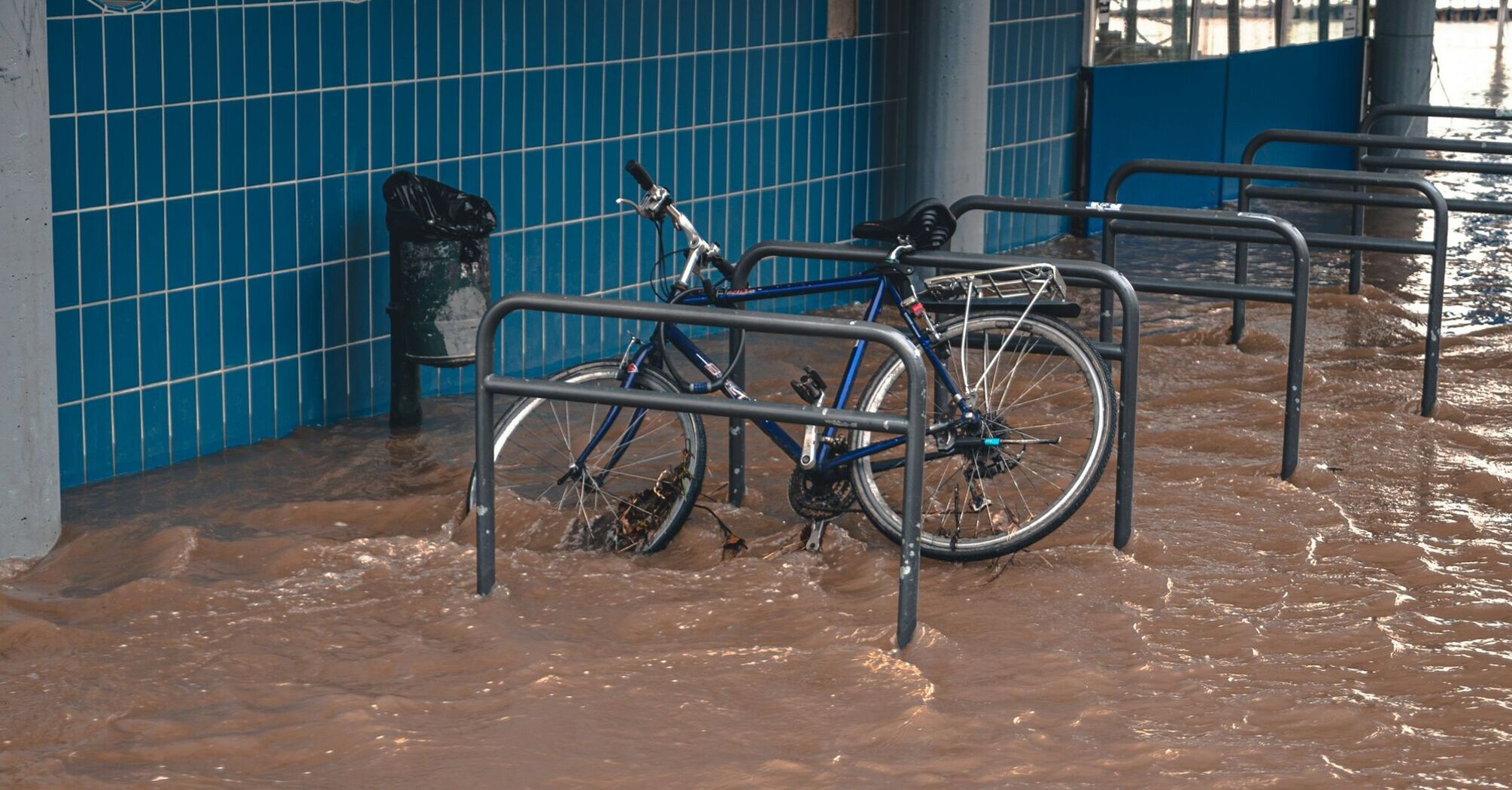 Bicycle partially submerged in floodwaters near a building