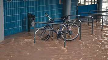 Bicycle partially submerged in floodwaters near a building
