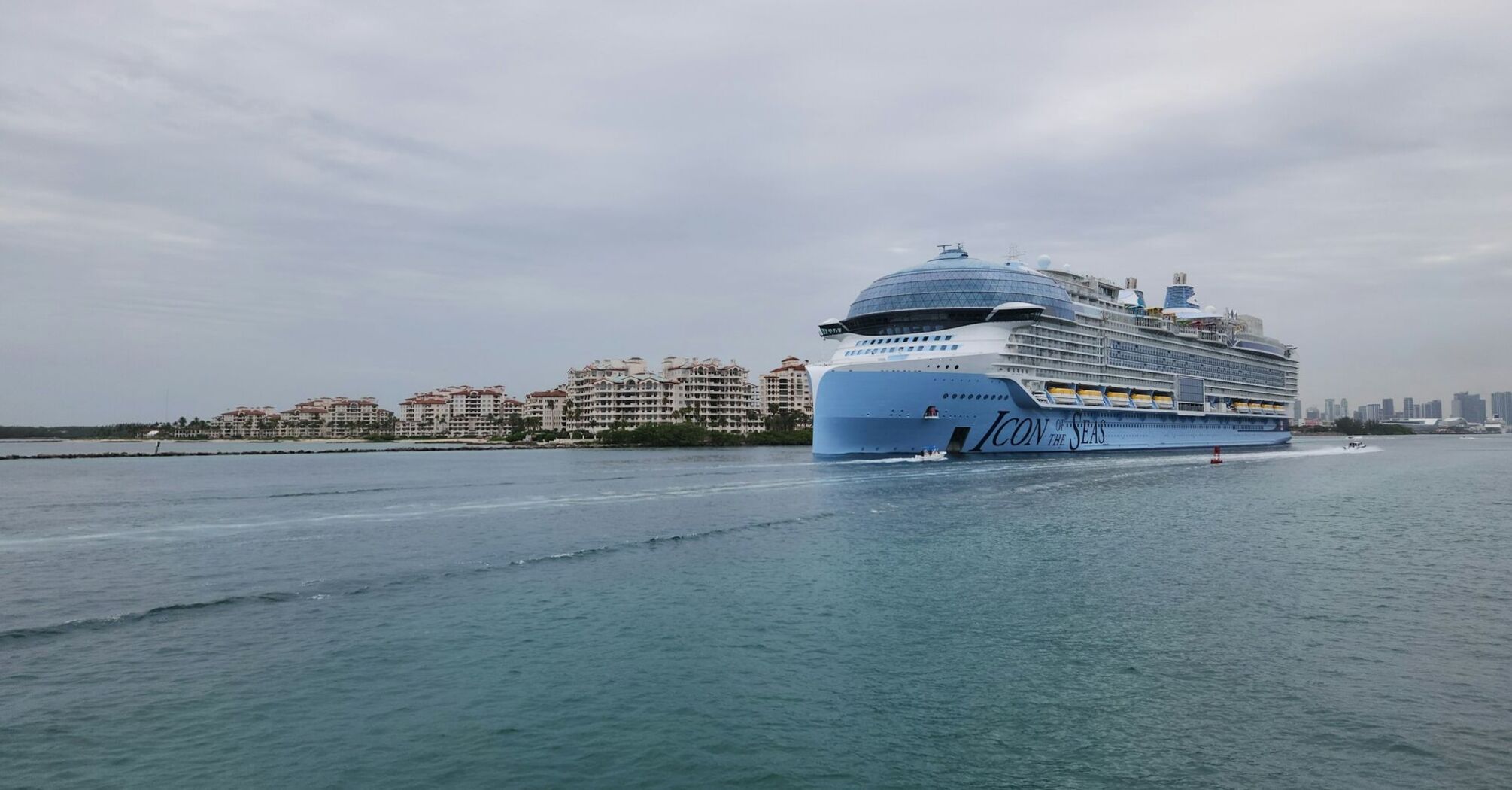 Icon of the Seas cruise ship sailing near a coastal city