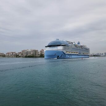 Icon of the Seas cruise ship sailing near a coastal city
