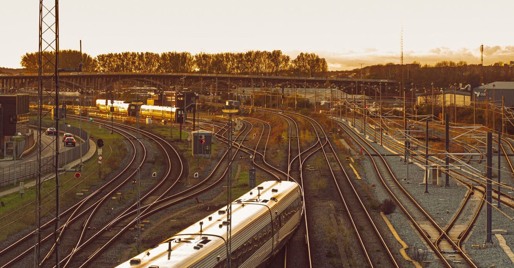 A sleek modern train in Denmark travels along railway tracks at sunset, highlighting cross-border rail connectivity