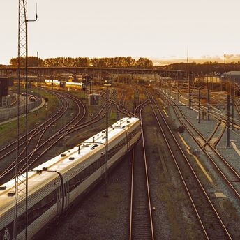 A sleek modern train in Denmark travels along railway tracks at sunset, highlighting cross-border rail connectivity