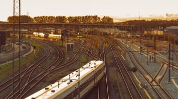 A sleek modern train in Denmark travels along railway tracks at sunset, highlighting cross-border rail connectivity