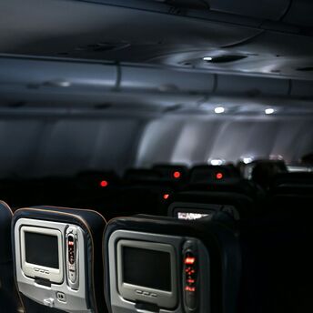 Empty seats and entertainment screens inside a dimly lit airplane cabin