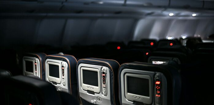 Empty seats and entertainment screens inside a dimly lit airplane cabin