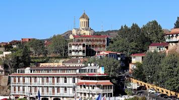 A scenic view of Tbilisi, showing traditional architecture and the Holy Trinity Cathedral overlooking the city