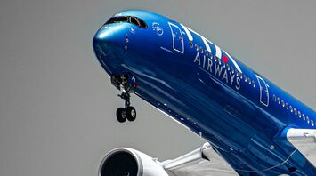 A blue ITA Airways plane flying in mid-air, approaching for landing
