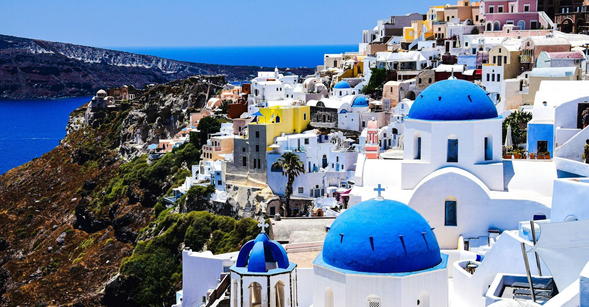 Whitewashed houses with blue domes on a cliff in Santorini