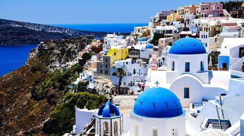 Whitewashed houses with blue domes on a cliff in Santorini