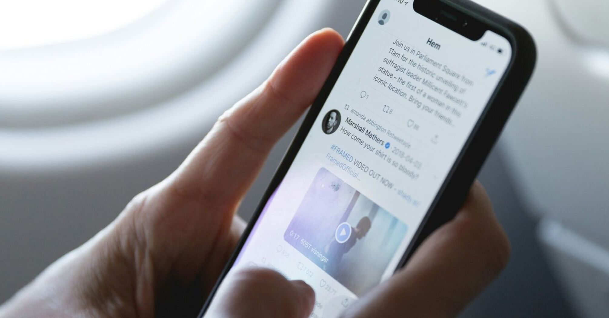 Person scrolling through Twitter on a smartphone during a flight