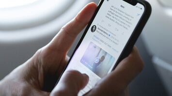 Person scrolling through Twitter on a smartphone during a flight