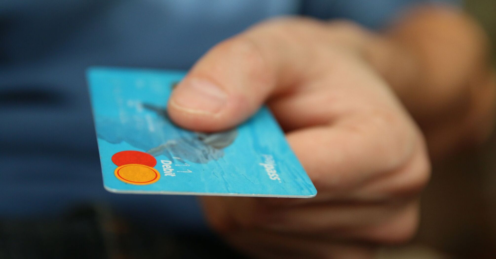 Hand holding a blue debit card